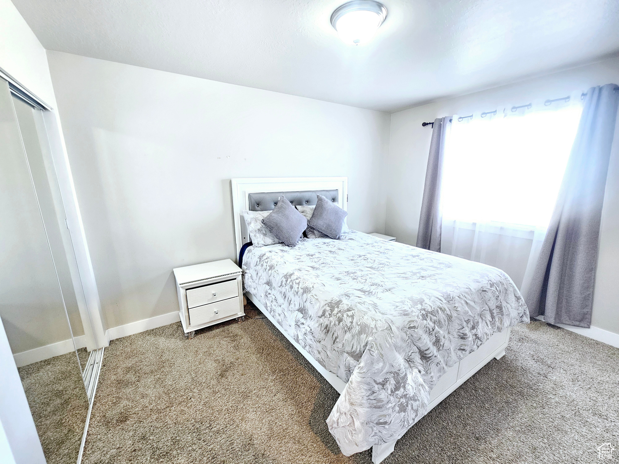 Carpeted bedroom with a closet and baseboards