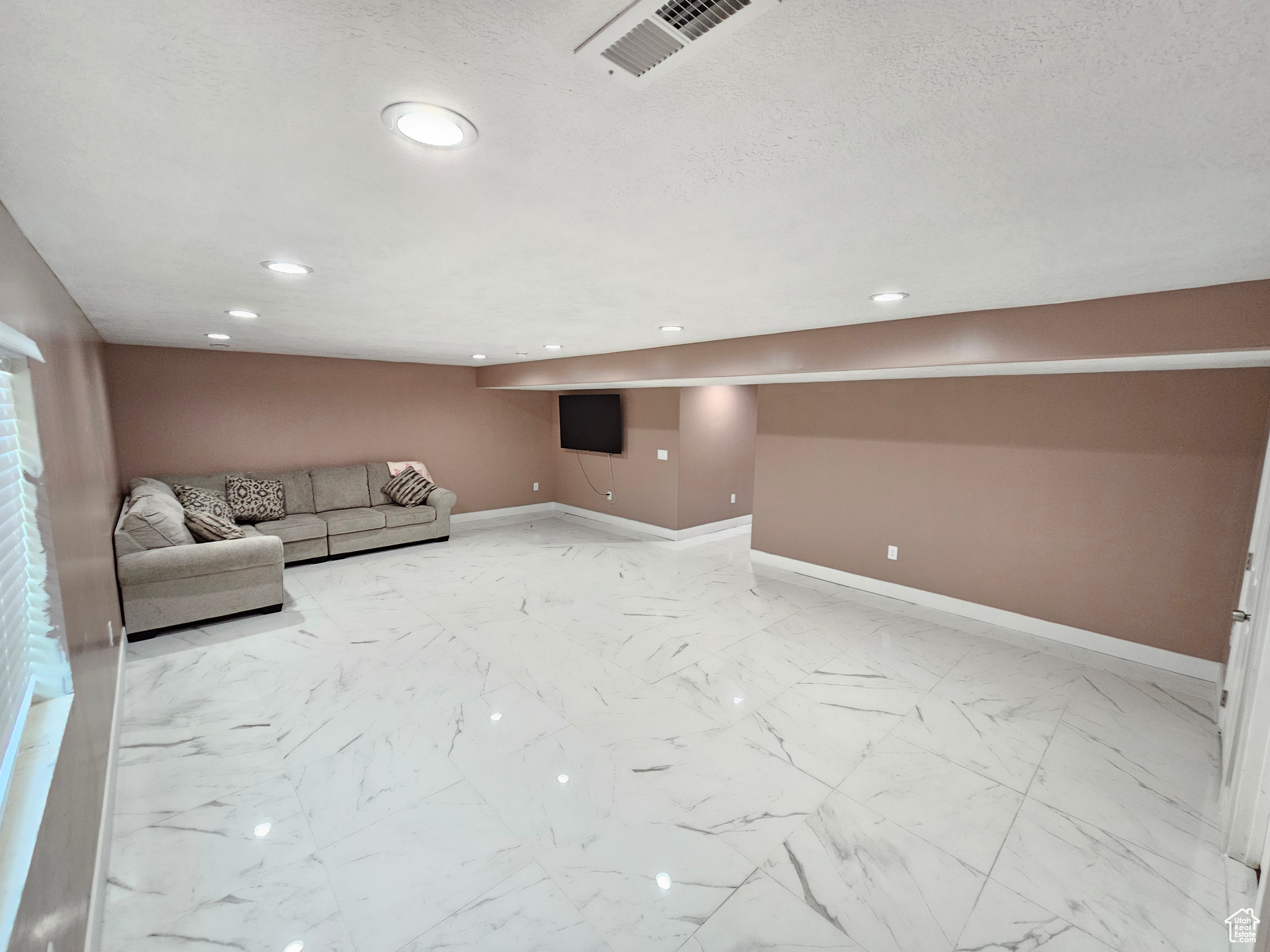 Unfurnished living room with visible vents, baseboards, marble finish floor, a textured ceiling, and recessed lighting