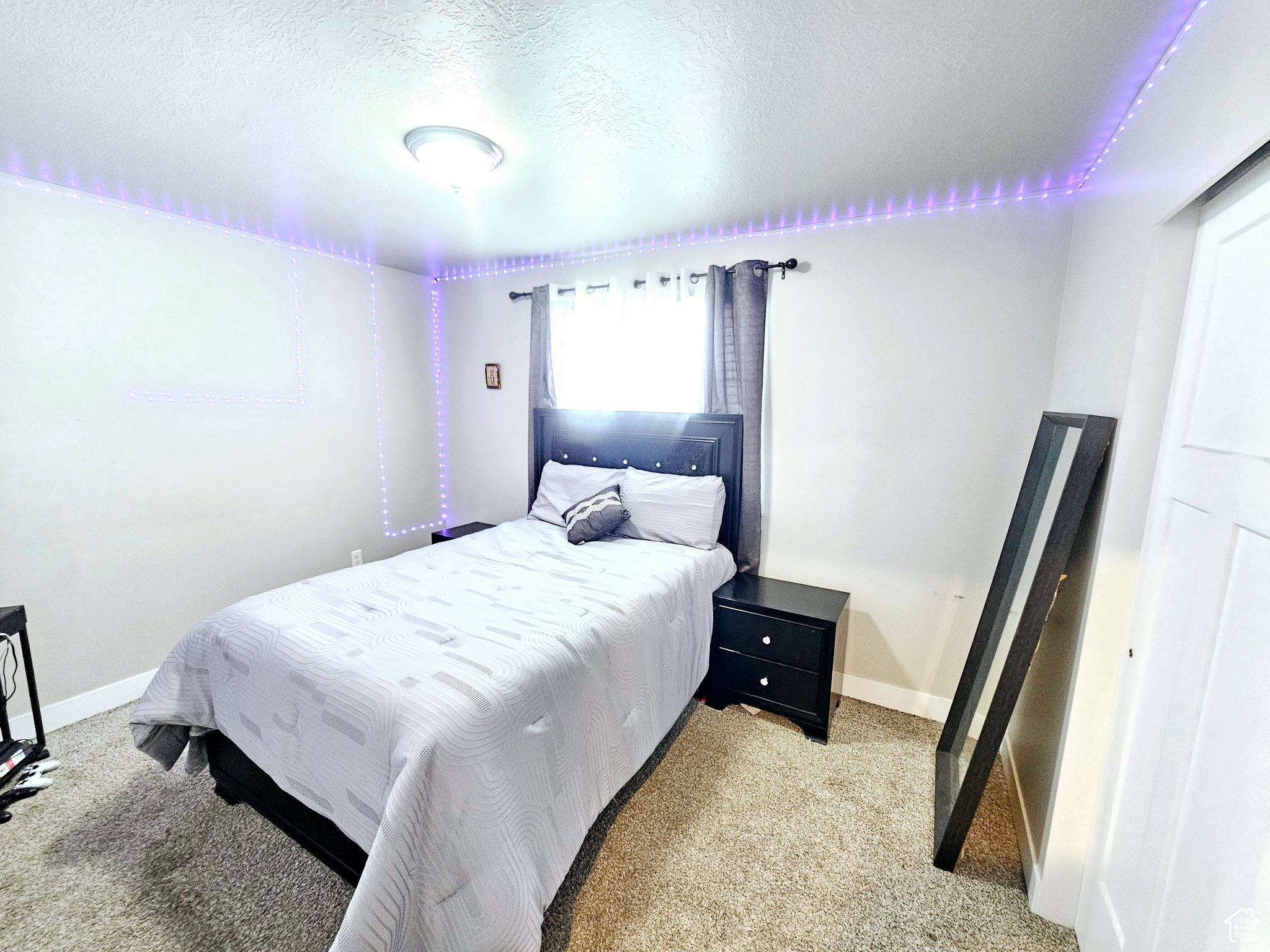 Bedroom with light carpet, a textured ceiling, and baseboards