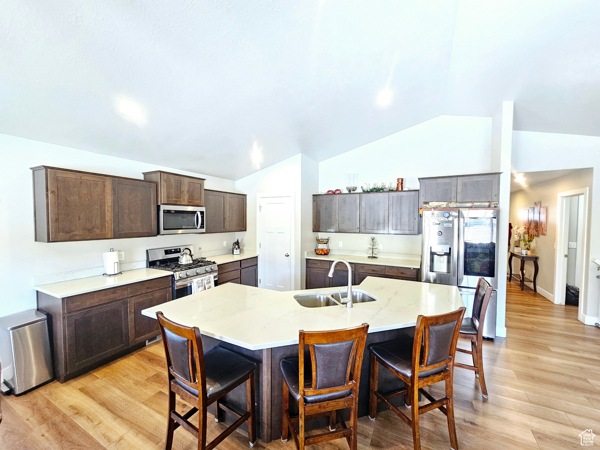 Kitchen with a breakfast bar area, a kitchen island with sink, dark brown cabinetry, stainless steel appliances, and a sink