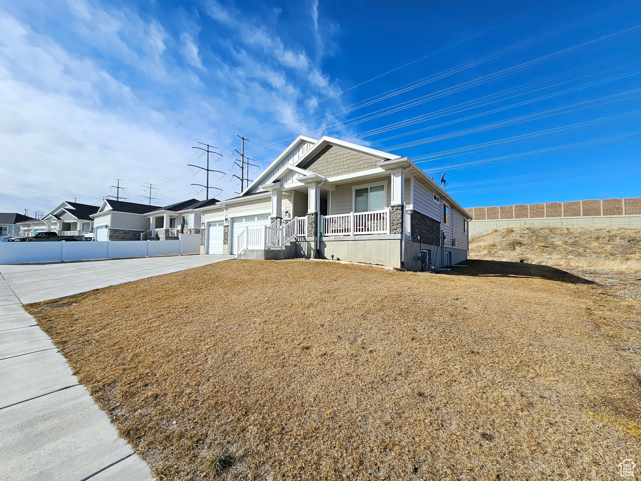 View of front of home with an attached garage, covered porch, fence, concrete driveway, and a front lawn
