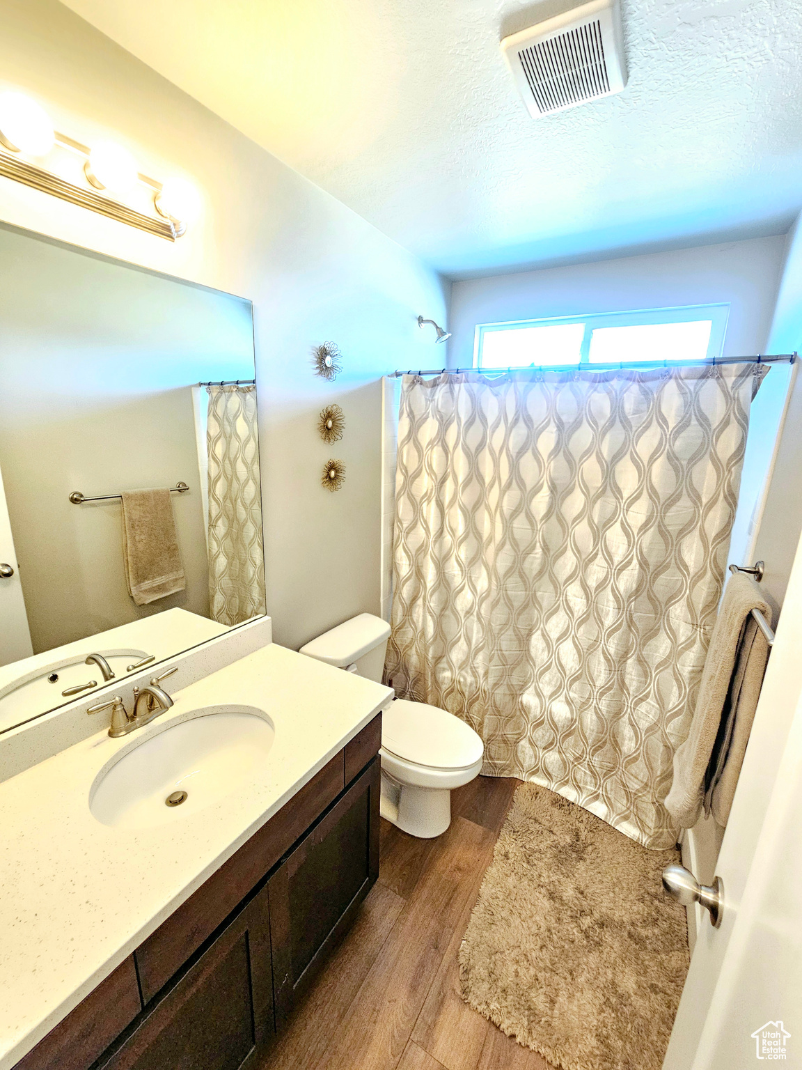 Full bath featuring visible vents, toilet, wood finished floors, a textured ceiling, and vanity