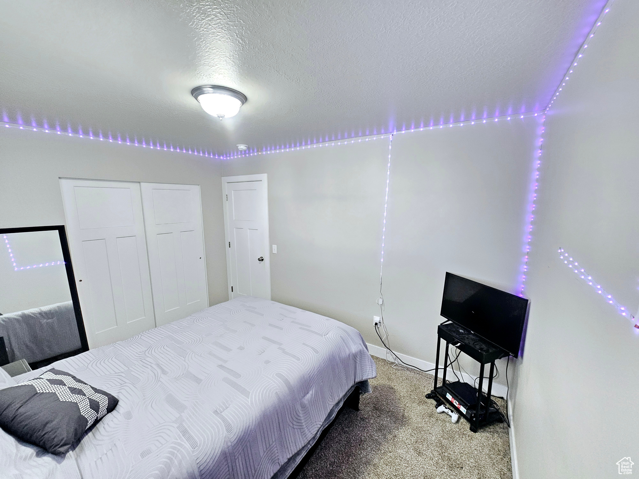 Bedroom with a textured ceiling, a closet, carpet flooring, and baseboards