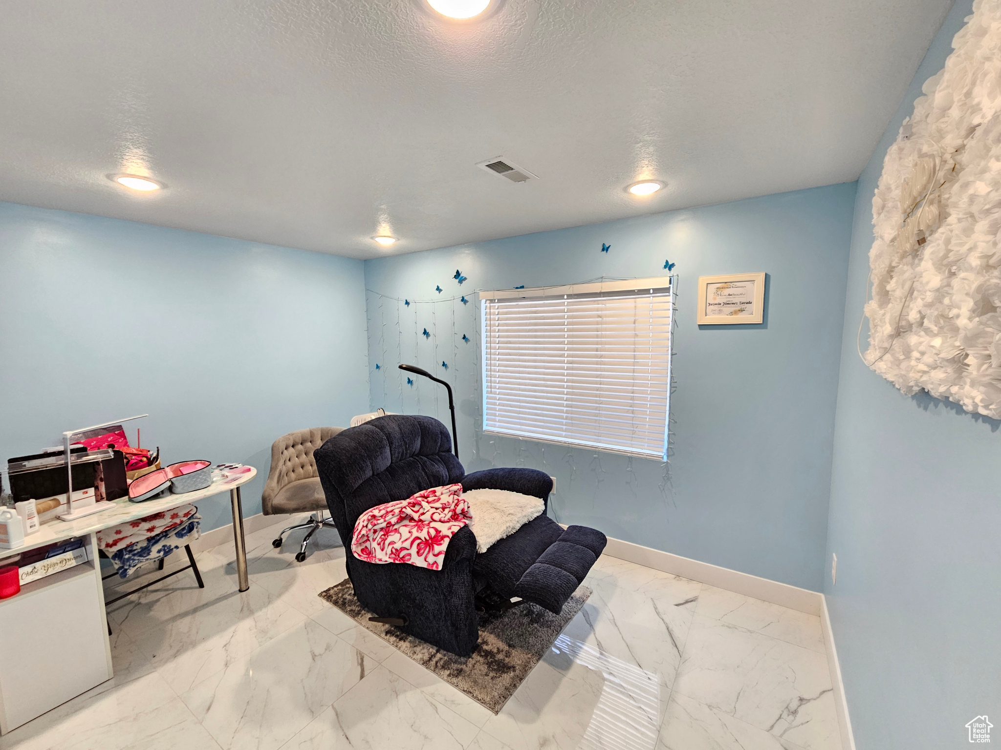 Living area featuring marble finish floor, baseboards, visible vents, and a textured ceiling