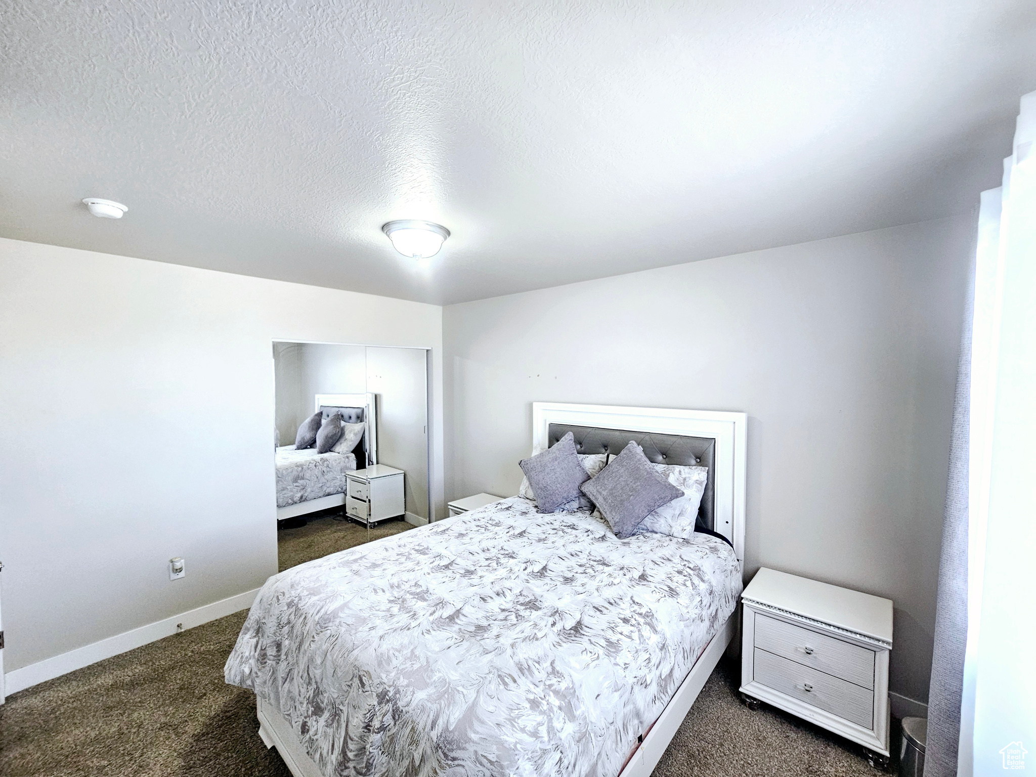 Bedroom with a closet, baseboards, dark colored carpet, and a textured ceiling