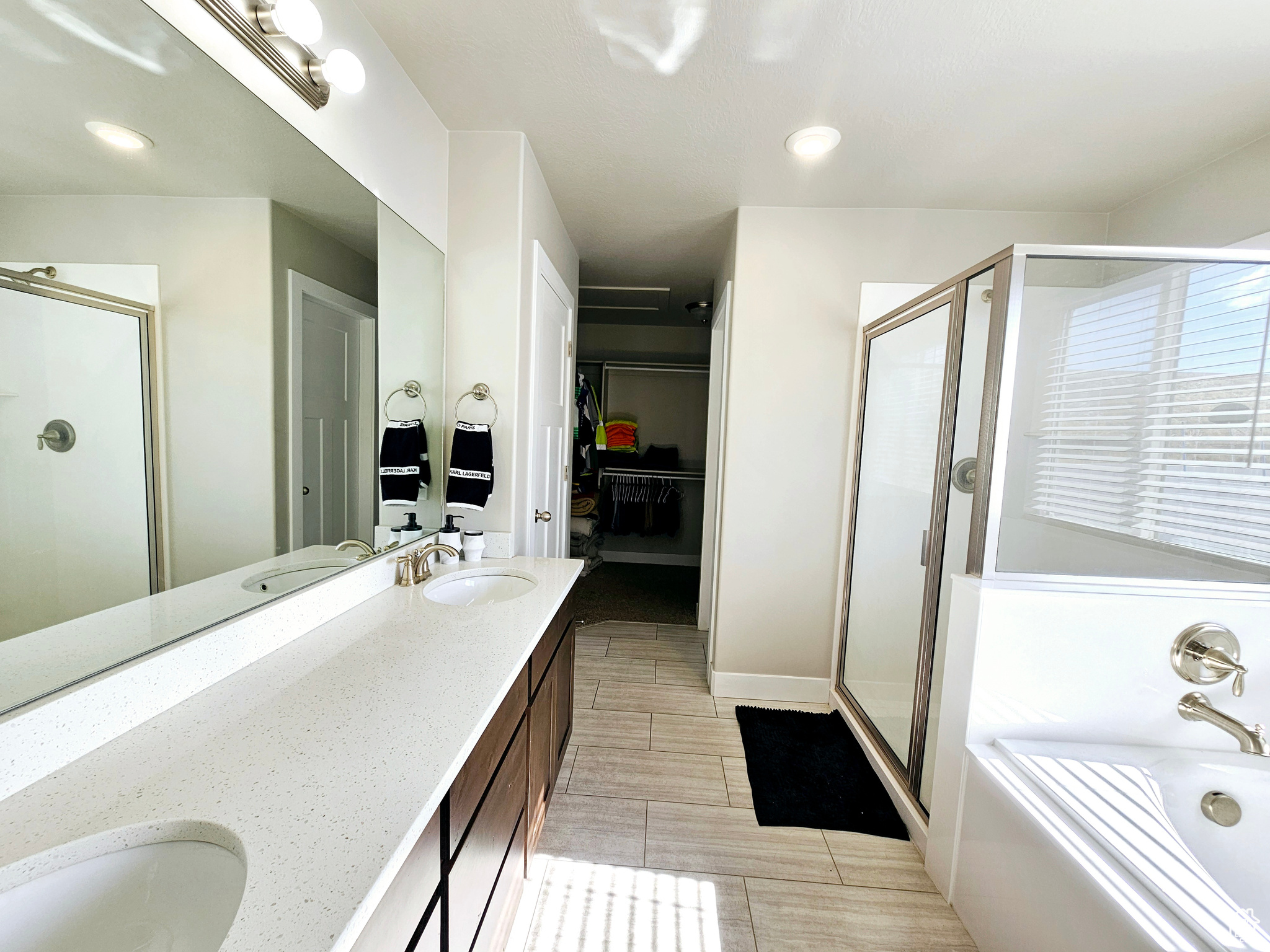 Bathroom with double vanity, a garden tub, a spacious closet, a shower stall, and a sink