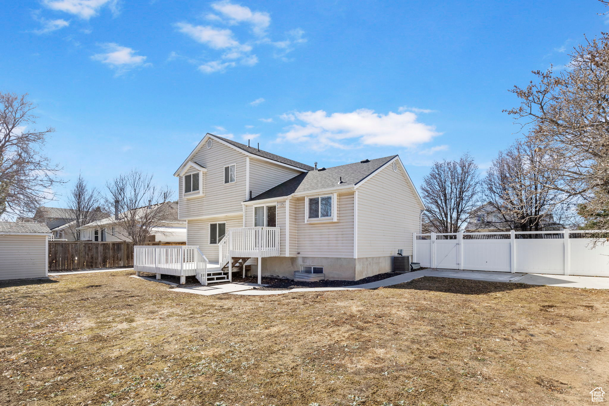 Rear view of property featuring a gate, a fenced backyard, and a yard