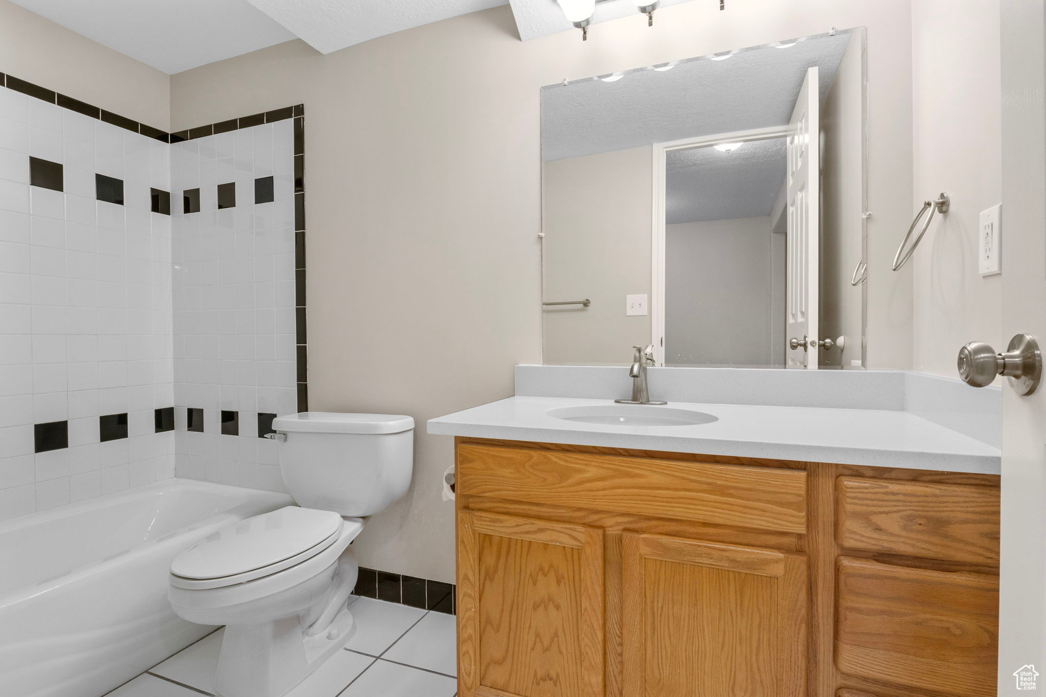 Bathroom with baseboards, bathing tub / shower combination, toilet, tile patterned flooring, and vanity