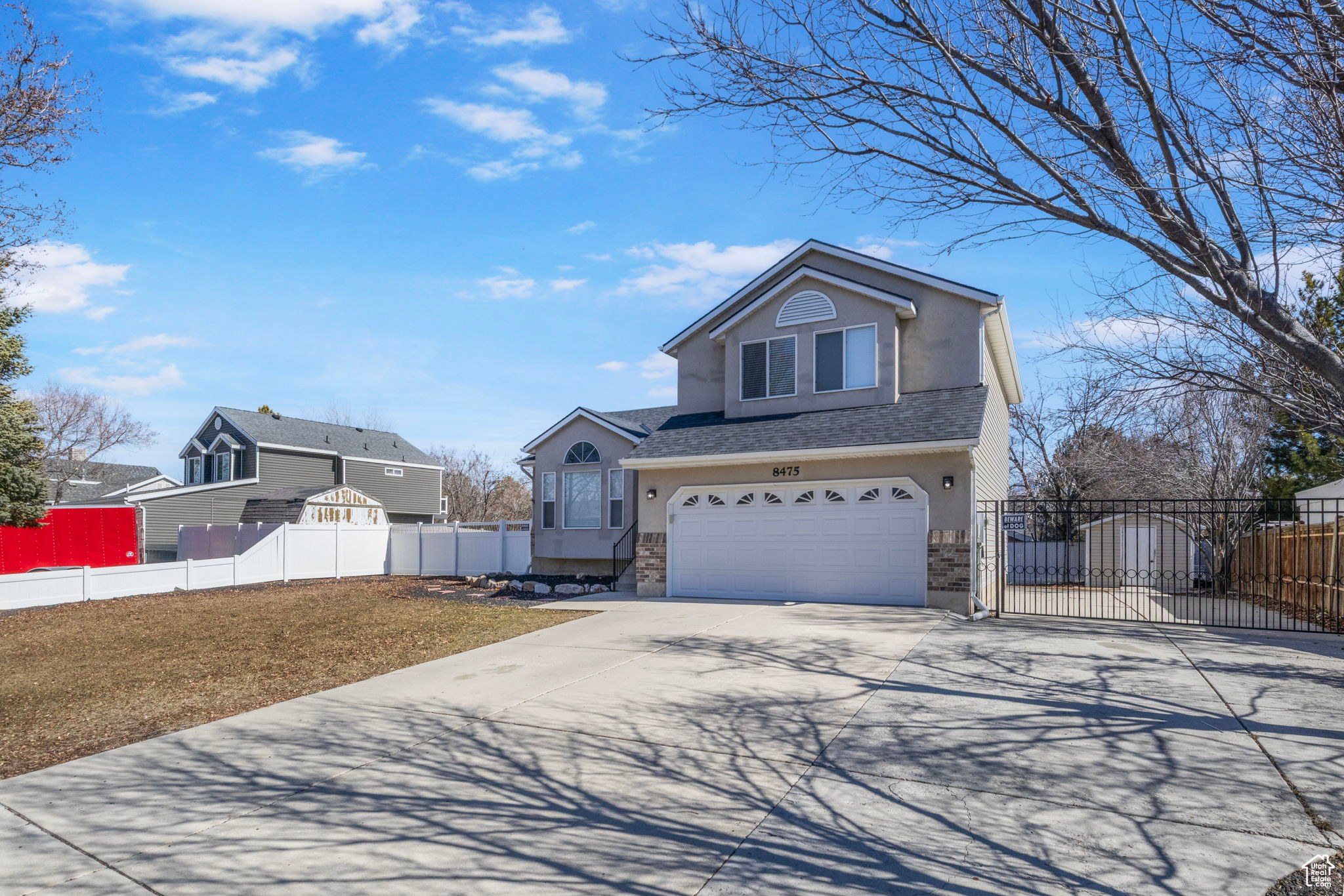 View of front facade featuring an attached garage, fence, driveway, stucco siding, and a front lawn