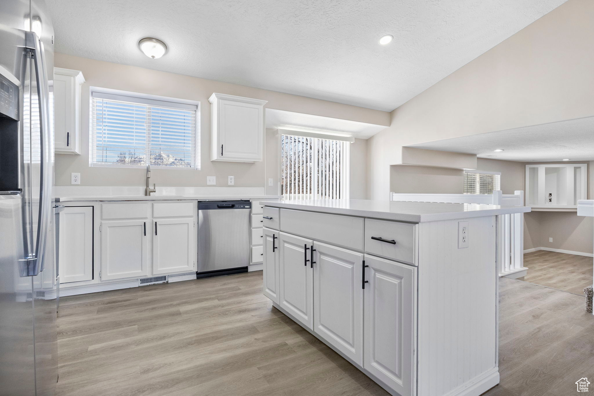 Kitchen featuring a center island, light countertops, appliances with stainless steel finishes, white cabinetry, and a sink