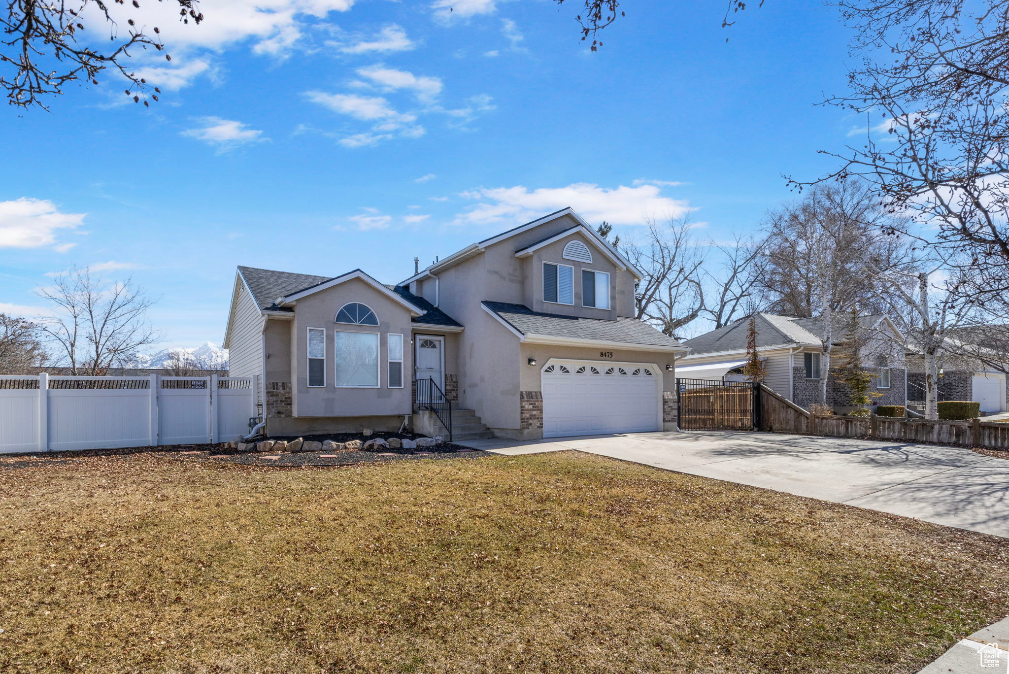 Traditional-style house featuring concrete driveway, an attached garage, fence, and a front yard