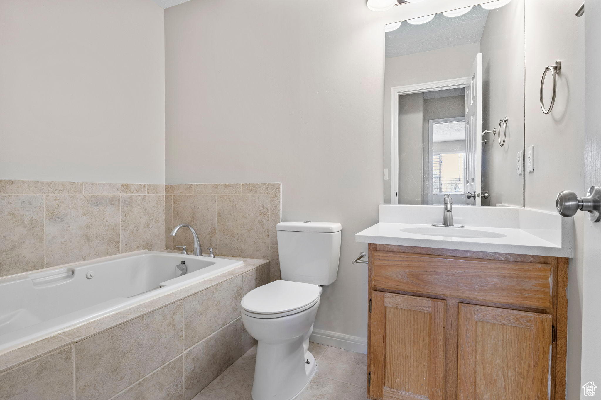 Bathroom featuring toilet, a garden tub, tile patterned flooring, and vanity