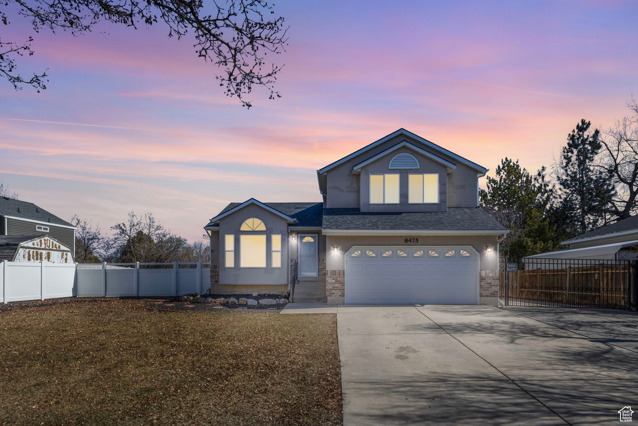 Traditional home featuring a front lawn, concrete driveway, fence, and an attached garage