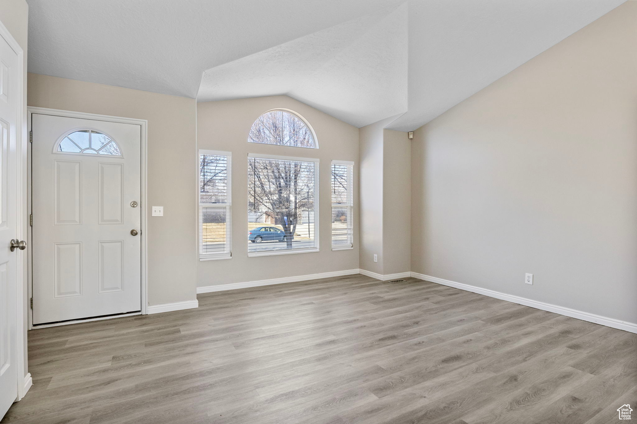 Foyer featuring vaulted ceiling, light wood finished floors, and baseboards