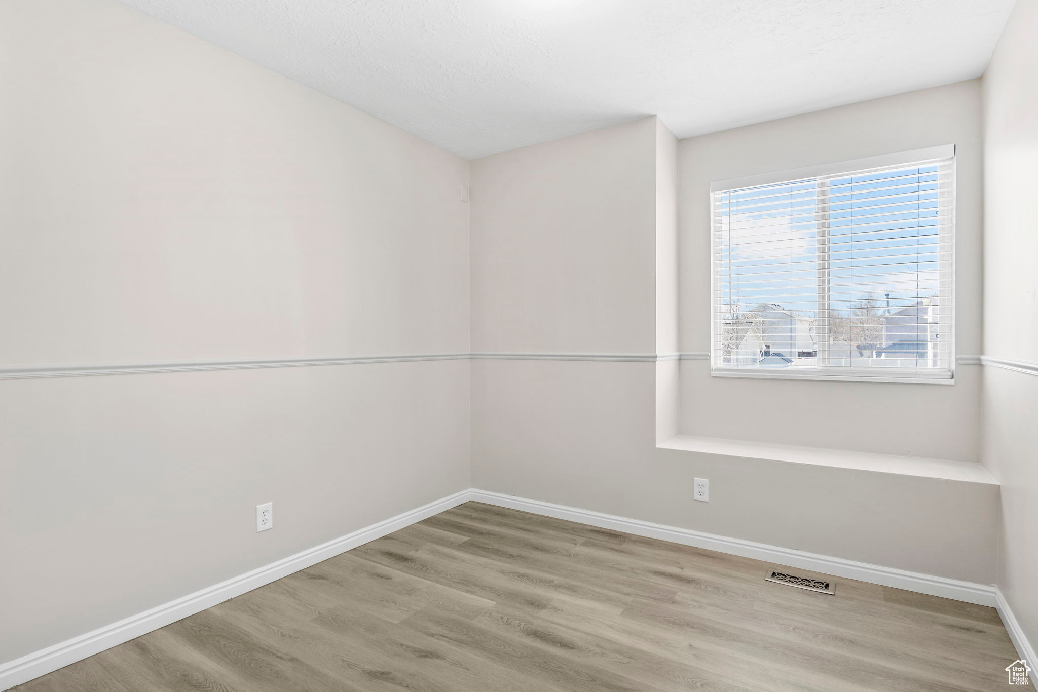 Spare room featuring visible vents, light wood-style flooring, and baseboards