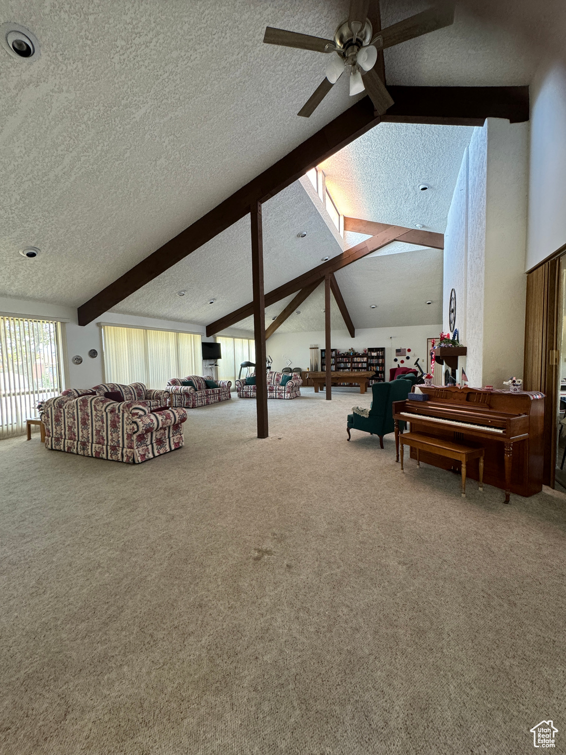 Living room with lofted ceiling with beams, ceiling fan, a textured ceiling, and carpet