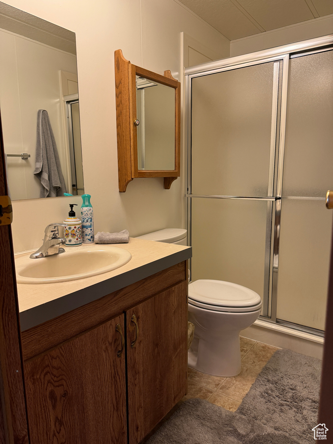 Bathroom featuring toilet, tile patterned floors, an enclosed shower, and vanity