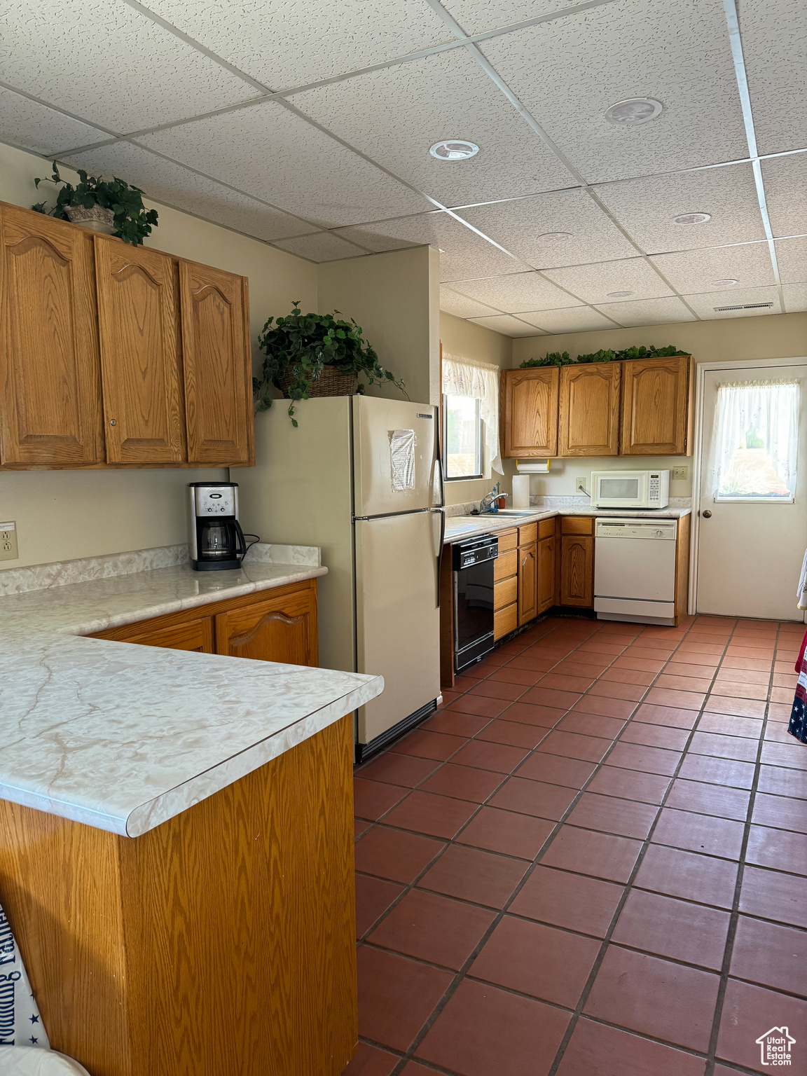 Kitchen featuring brown cabinets, white appliances, light countertops, and plenty of natural light