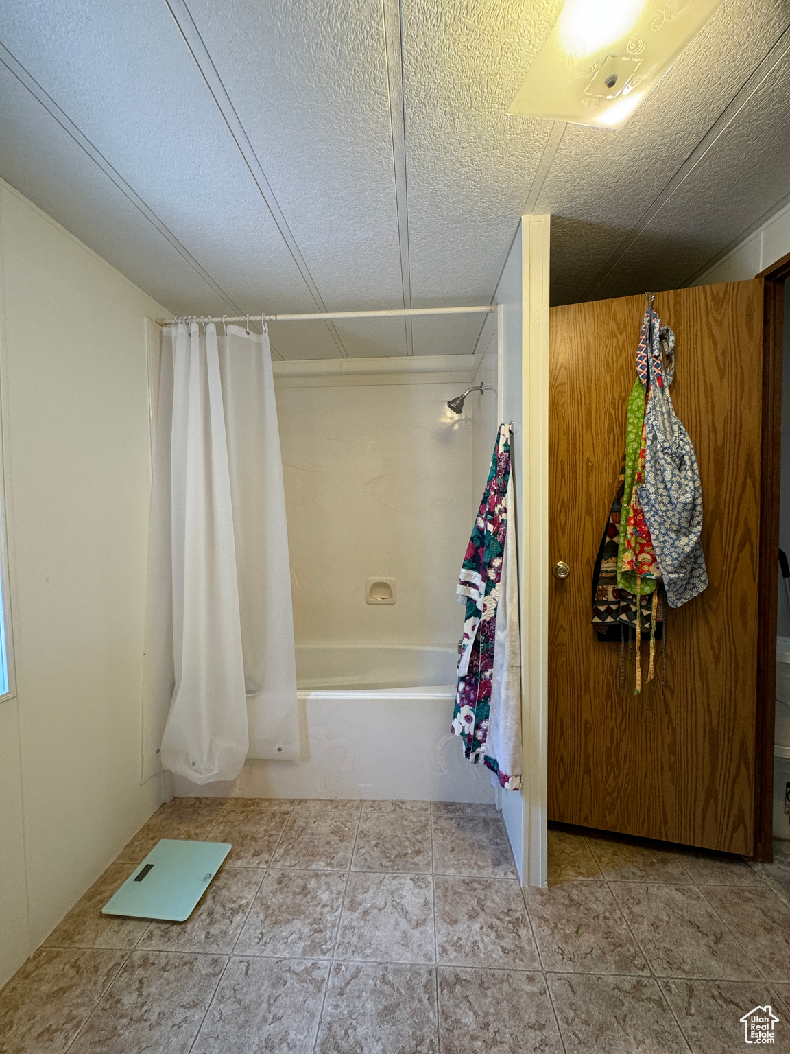 Bathroom featuring a textured ceiling, shower / tub combo, and tile patterned floors