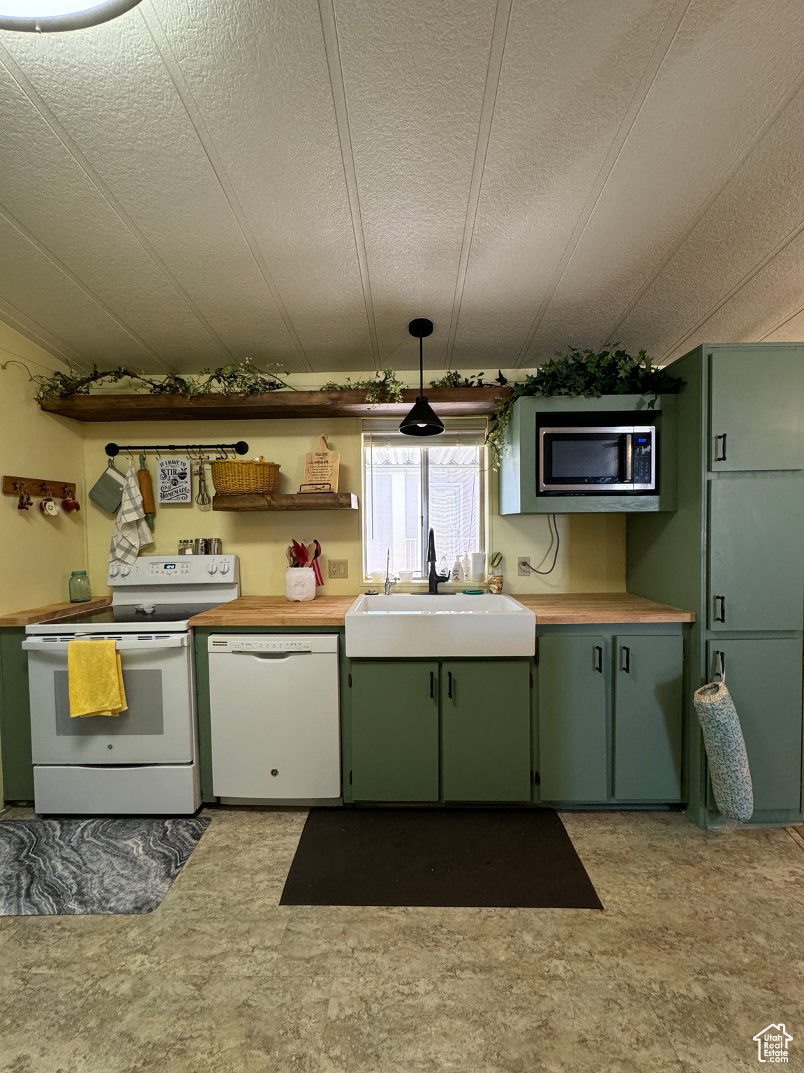 Kitchen featuring white appliances, light countertops, a sink, and green cabinetry