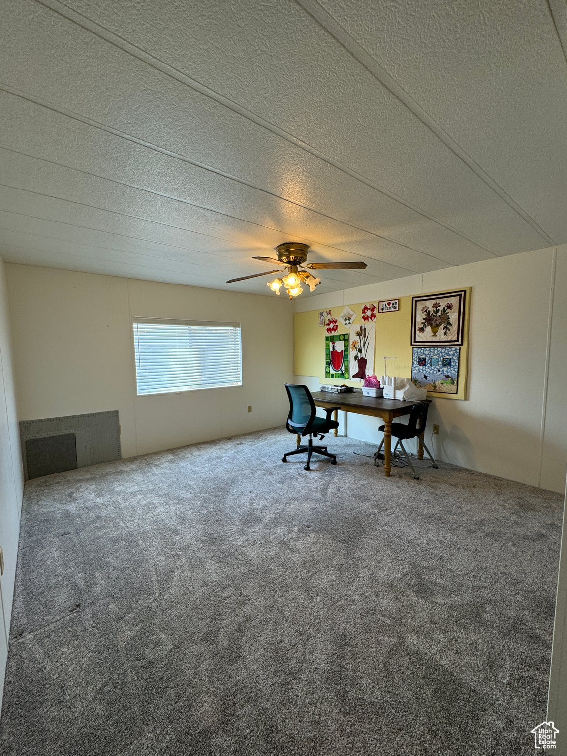 Interior space with a textured ceiling, carpet flooring, and a ceiling fan