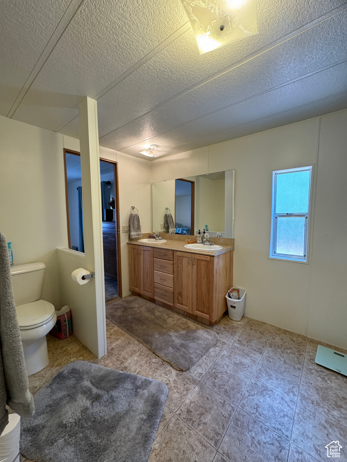 Full bath featuring a textured ceiling, double vanity, and a sink