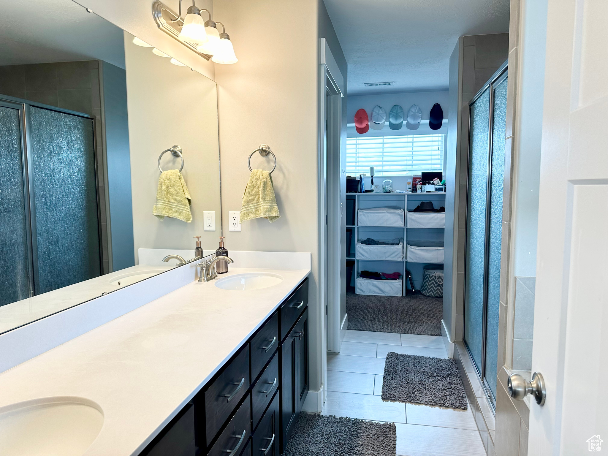 Full bath with tile patterned floors, a sink, a shower stall, and double vanity