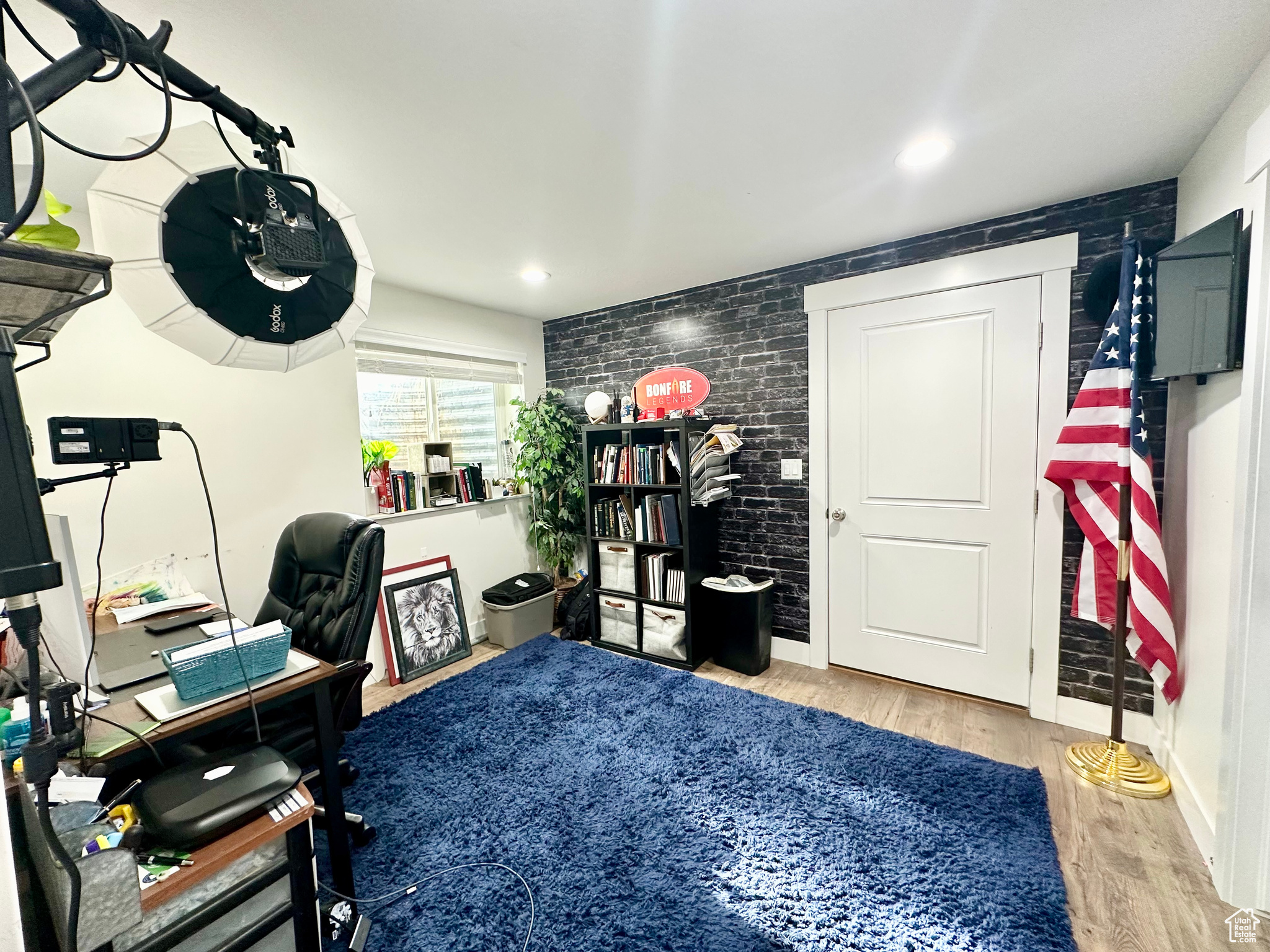 Home office with light wood-type flooring and brick wall