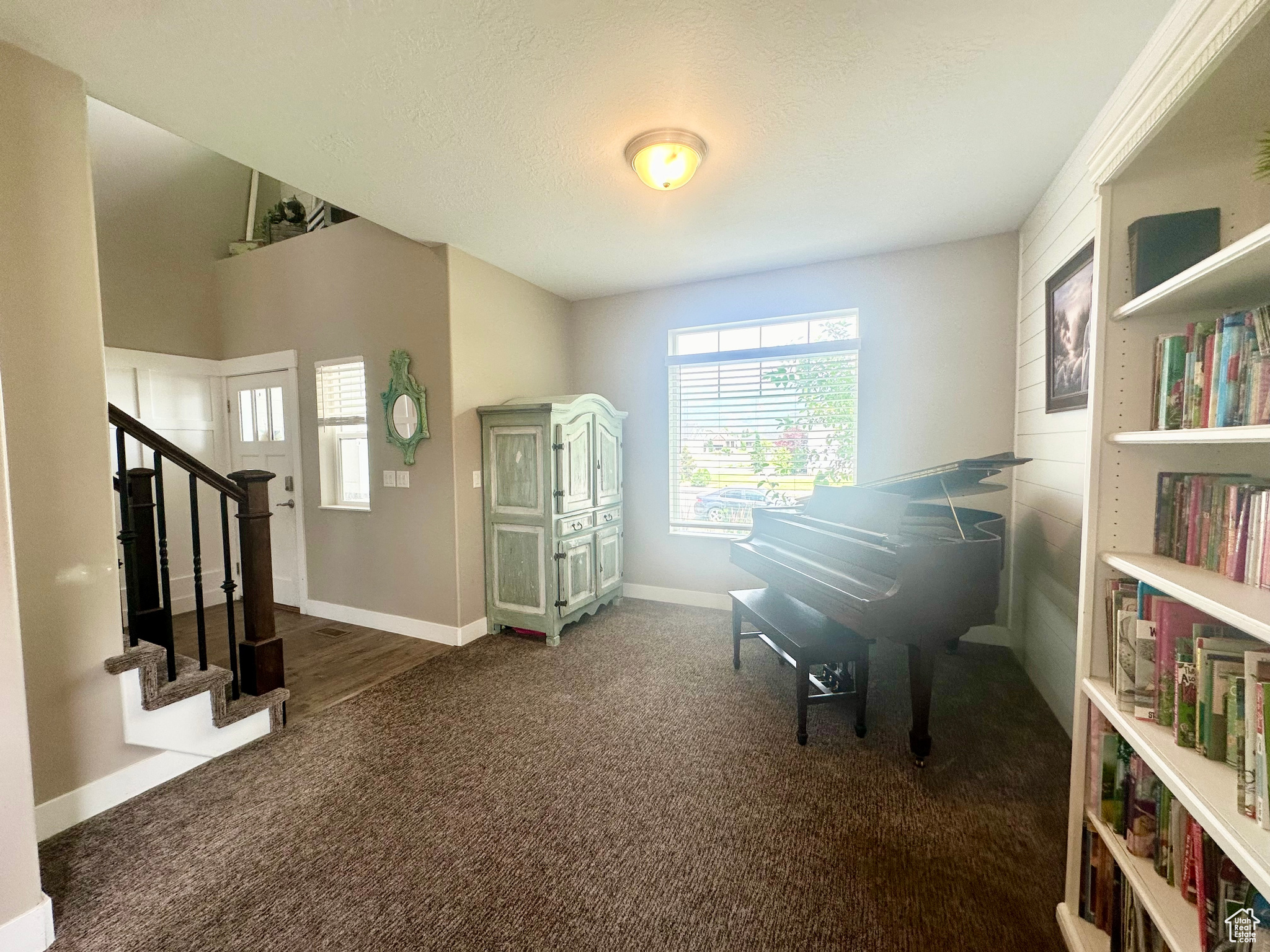Sitting room featuring a textured ceiling, stairway, dark carpet, and baseboards