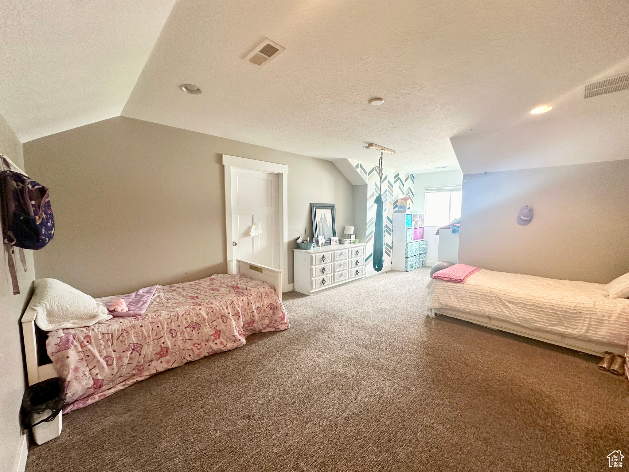 Bedroom featuring lofted ceiling, visible vents, a textured ceiling, and carpet flooring