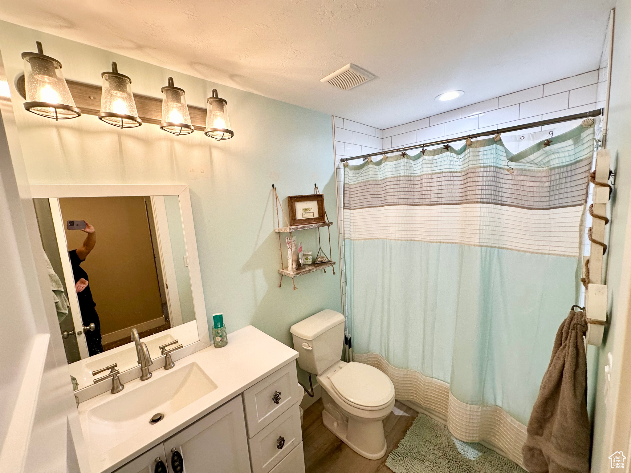 Full bath featuring curtained shower, visible vents, vanity, and toilet