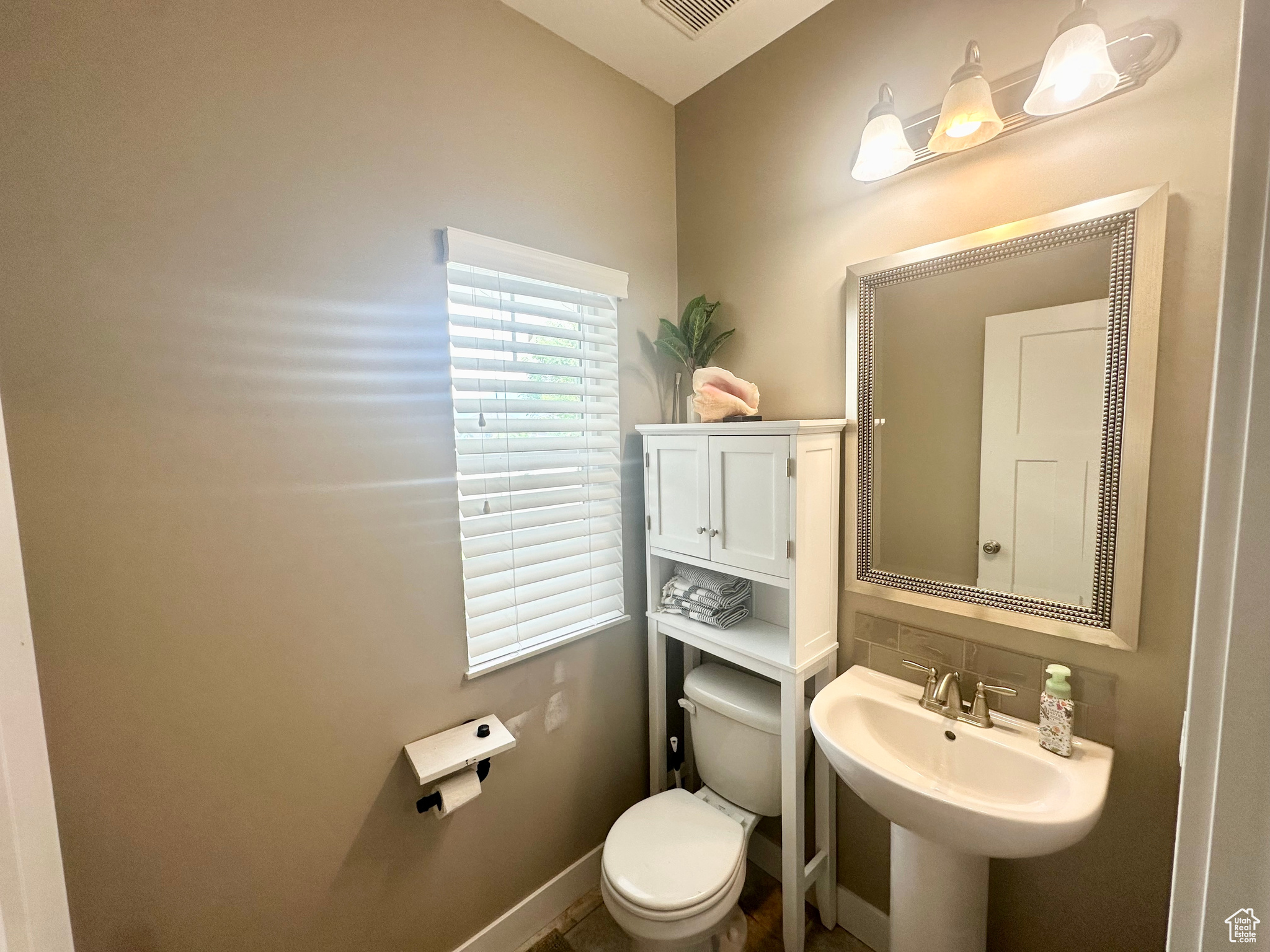 Half bath with baseboards, a sink, visible vents, and toilet