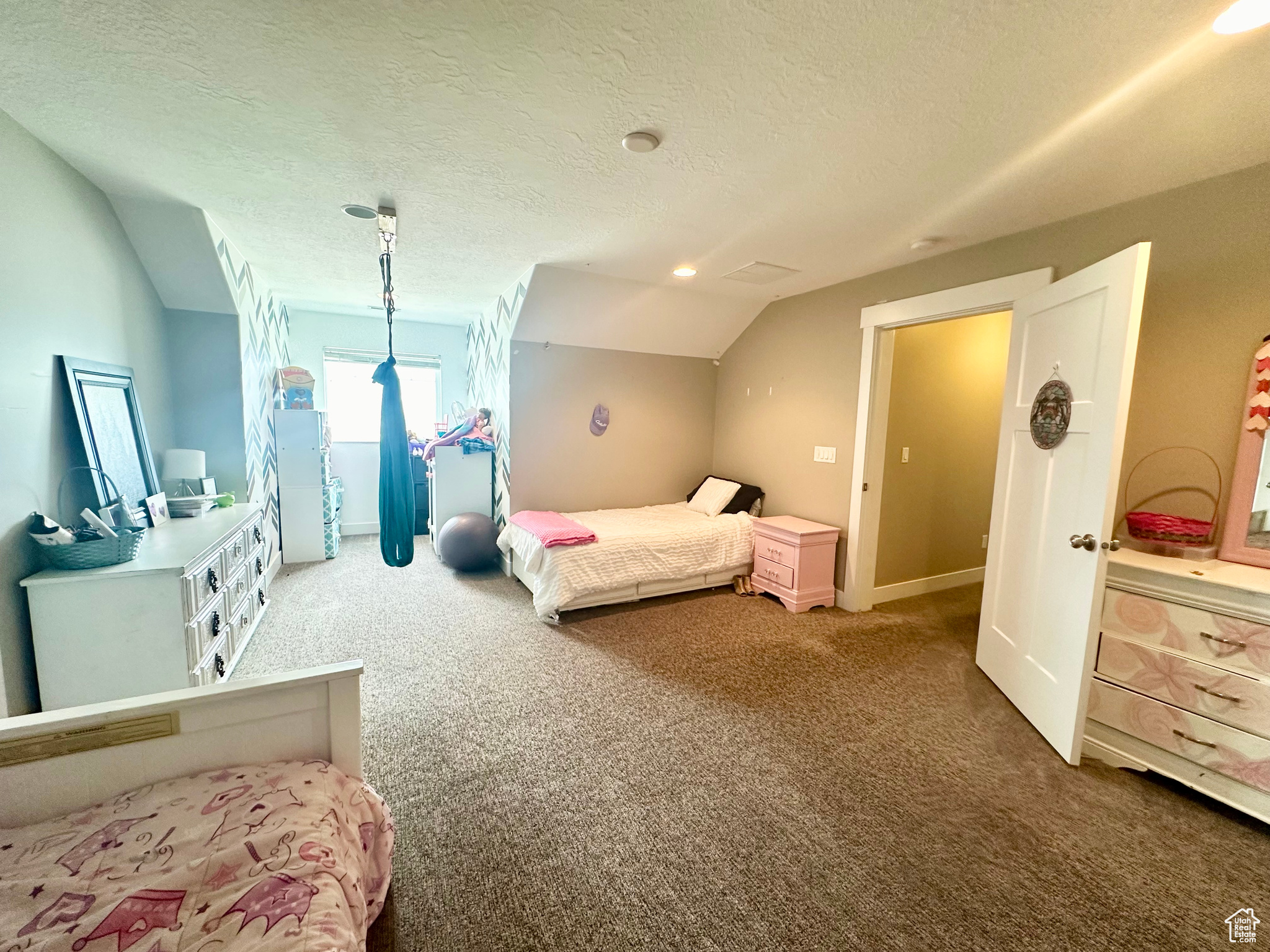 Carpeted bedroom featuring vaulted ceiling and a textured ceiling