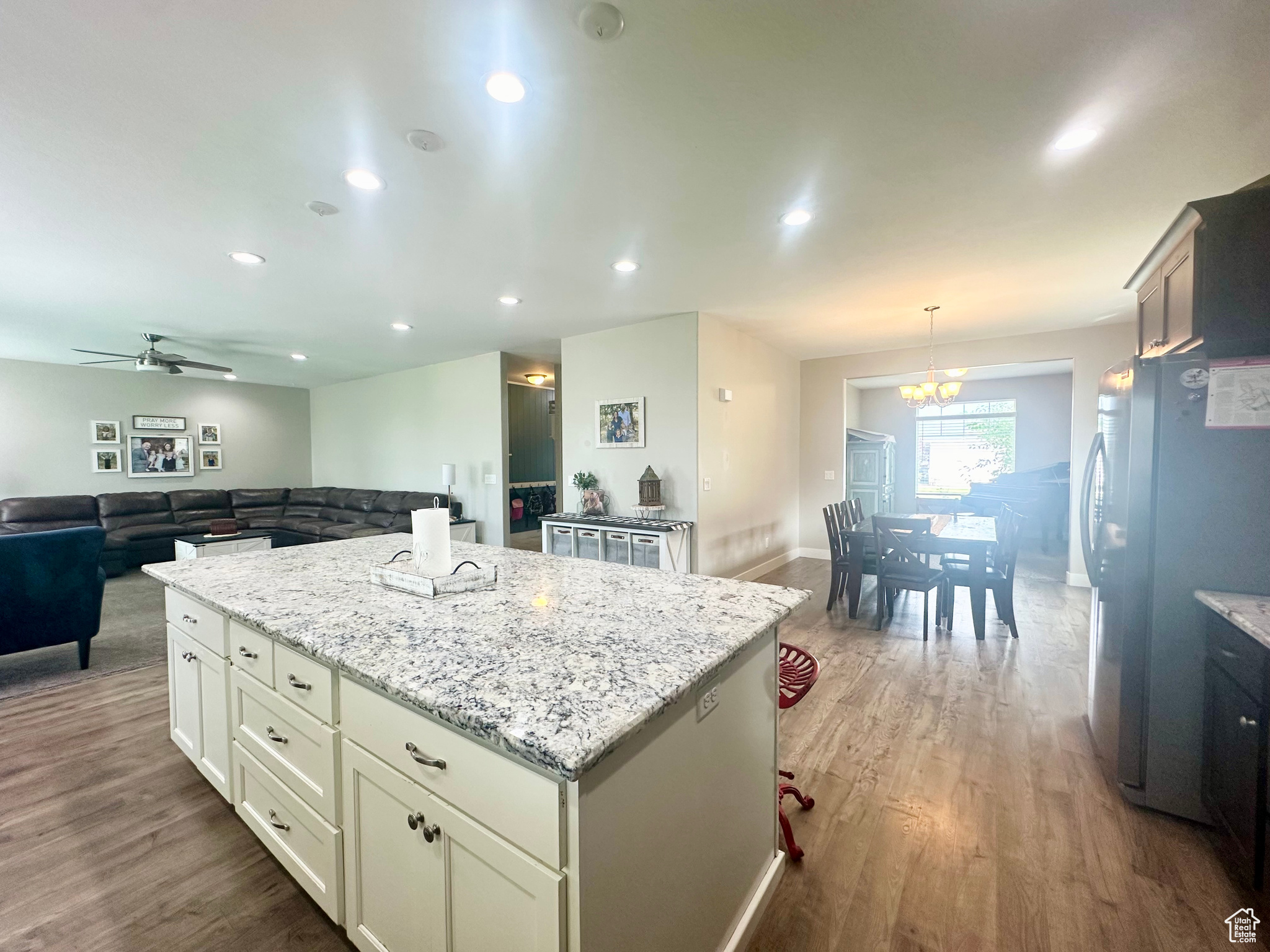 Kitchen featuring dark wood finished floors, light stone counters, open floor plan, decorative light fixtures, and freestanding refrigerator