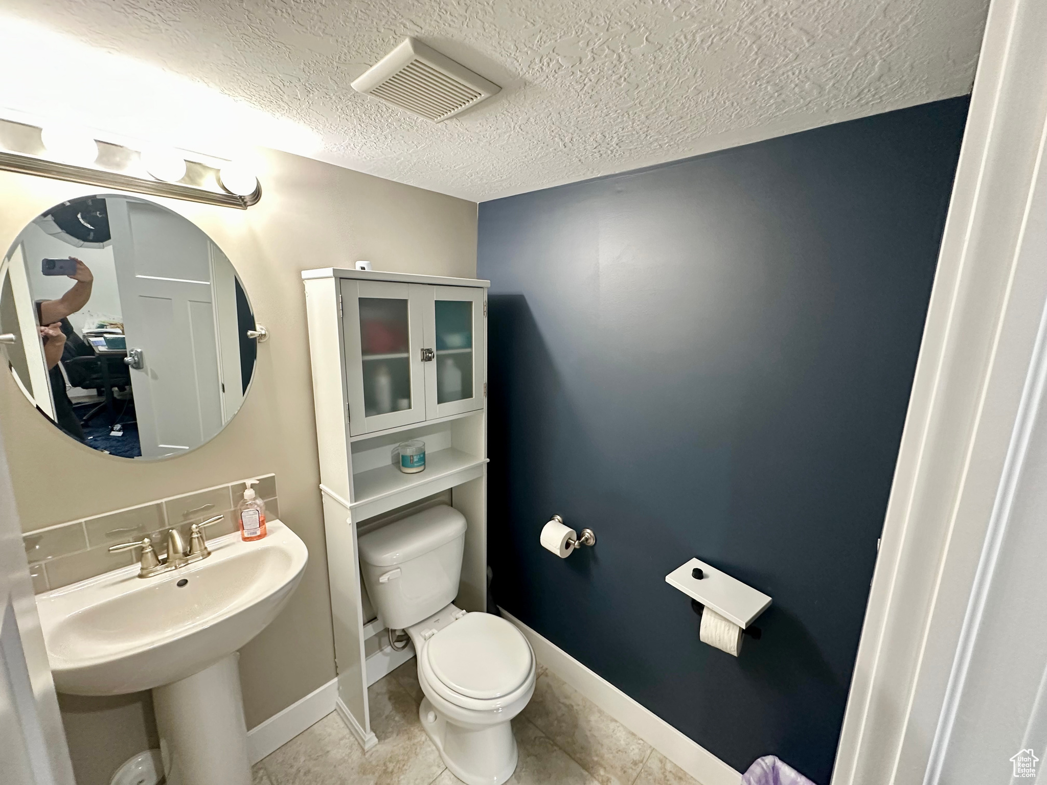 Half bathroom with a textured ceiling, tile patterned flooring, toilet, visible vents, and baseboards