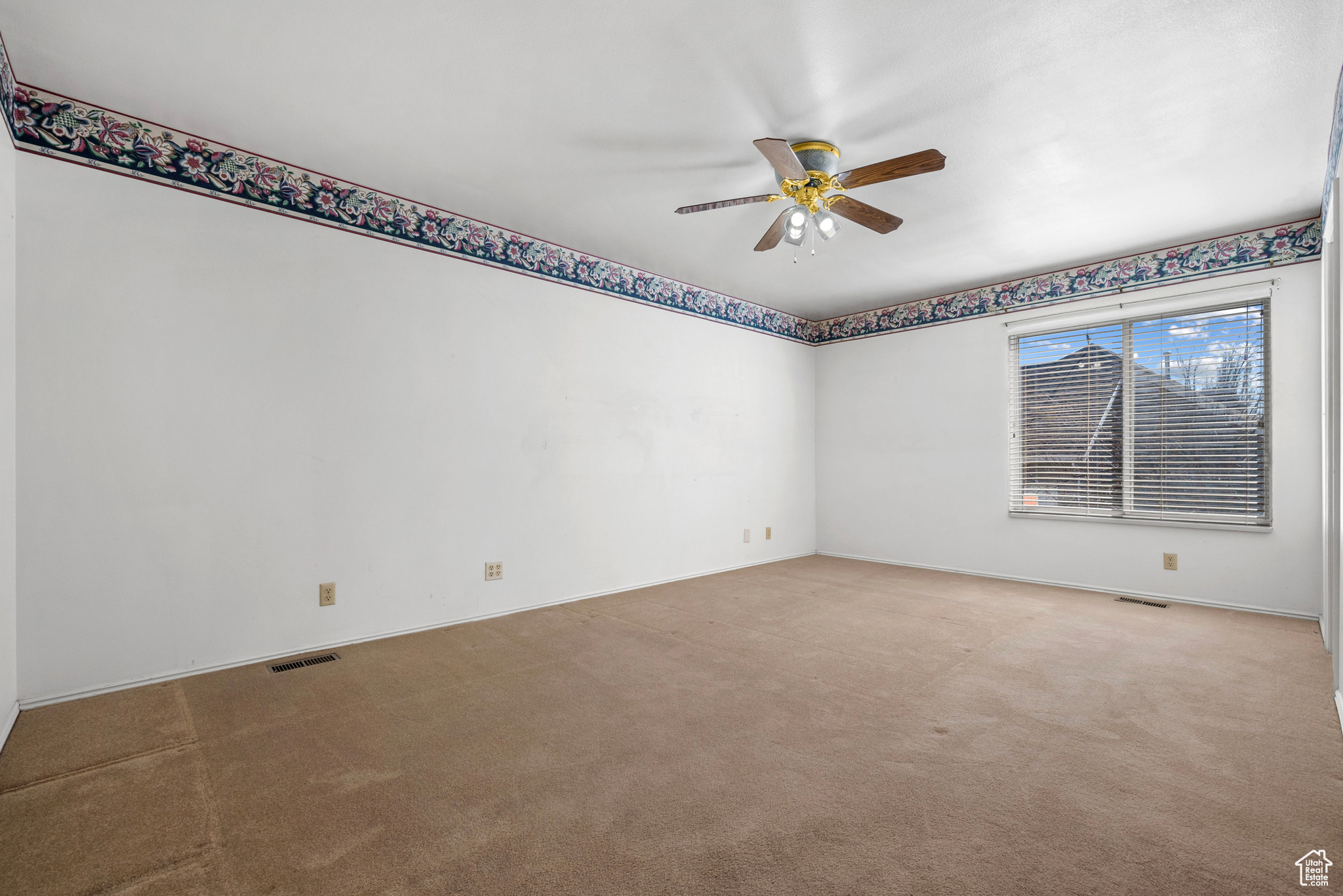 Unfurnished room featuring light carpet, baseboards, visible vents, and a ceiling fan