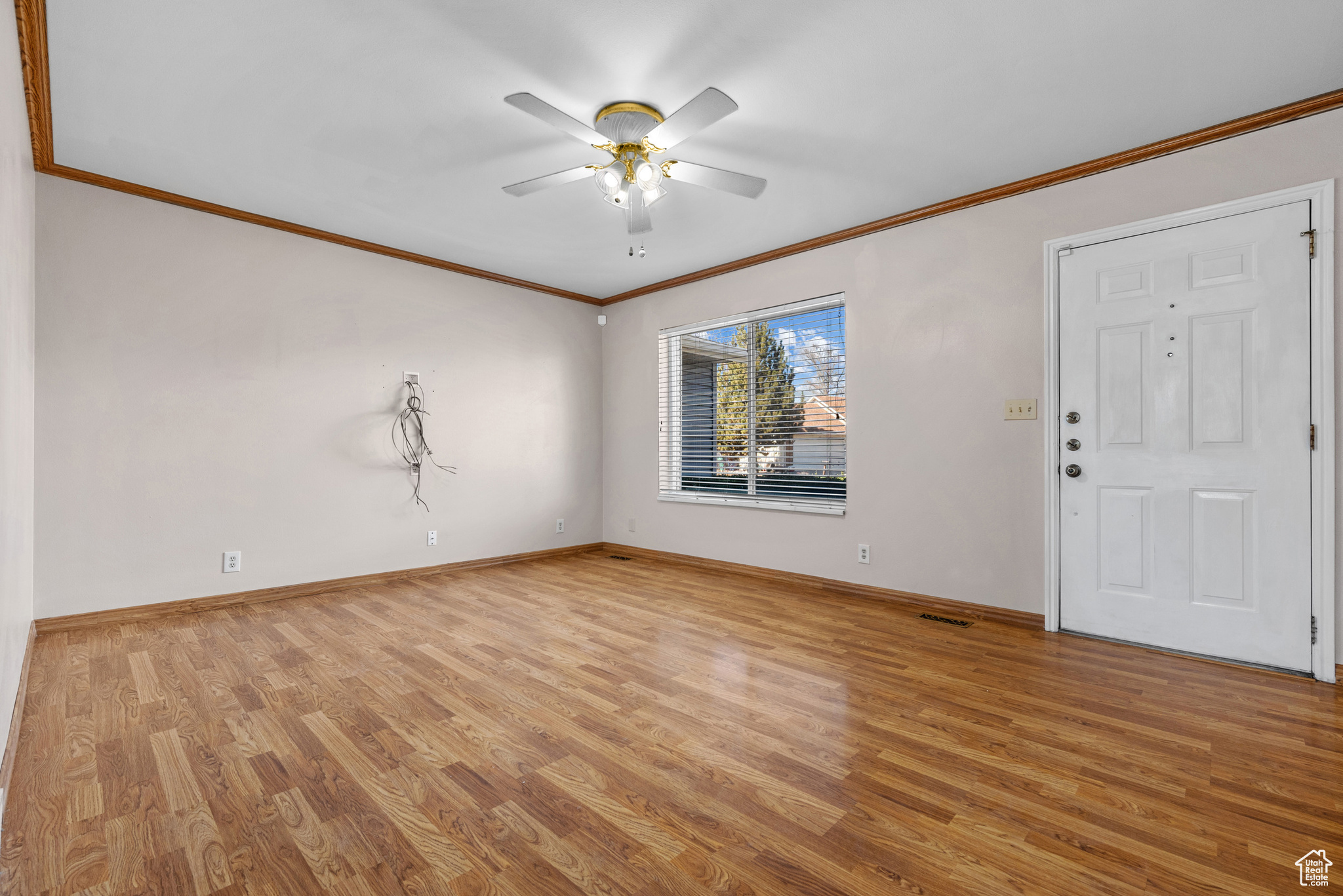 Interior space with ornamental molding, light wood finished floors, a ceiling fan, and baseboards