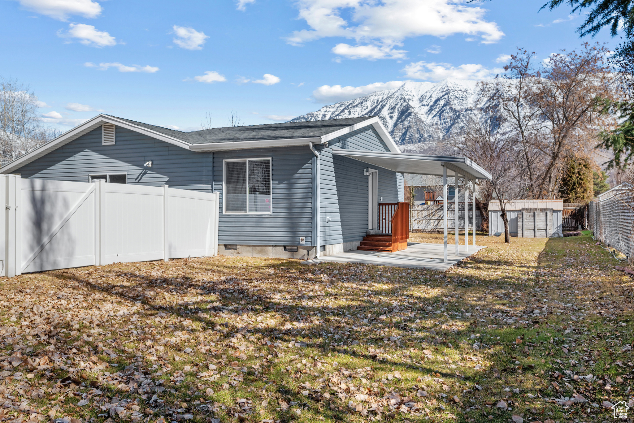 Exterior space with a fenced backyard, crawl space, a storage unit, a mountain view, and a carport