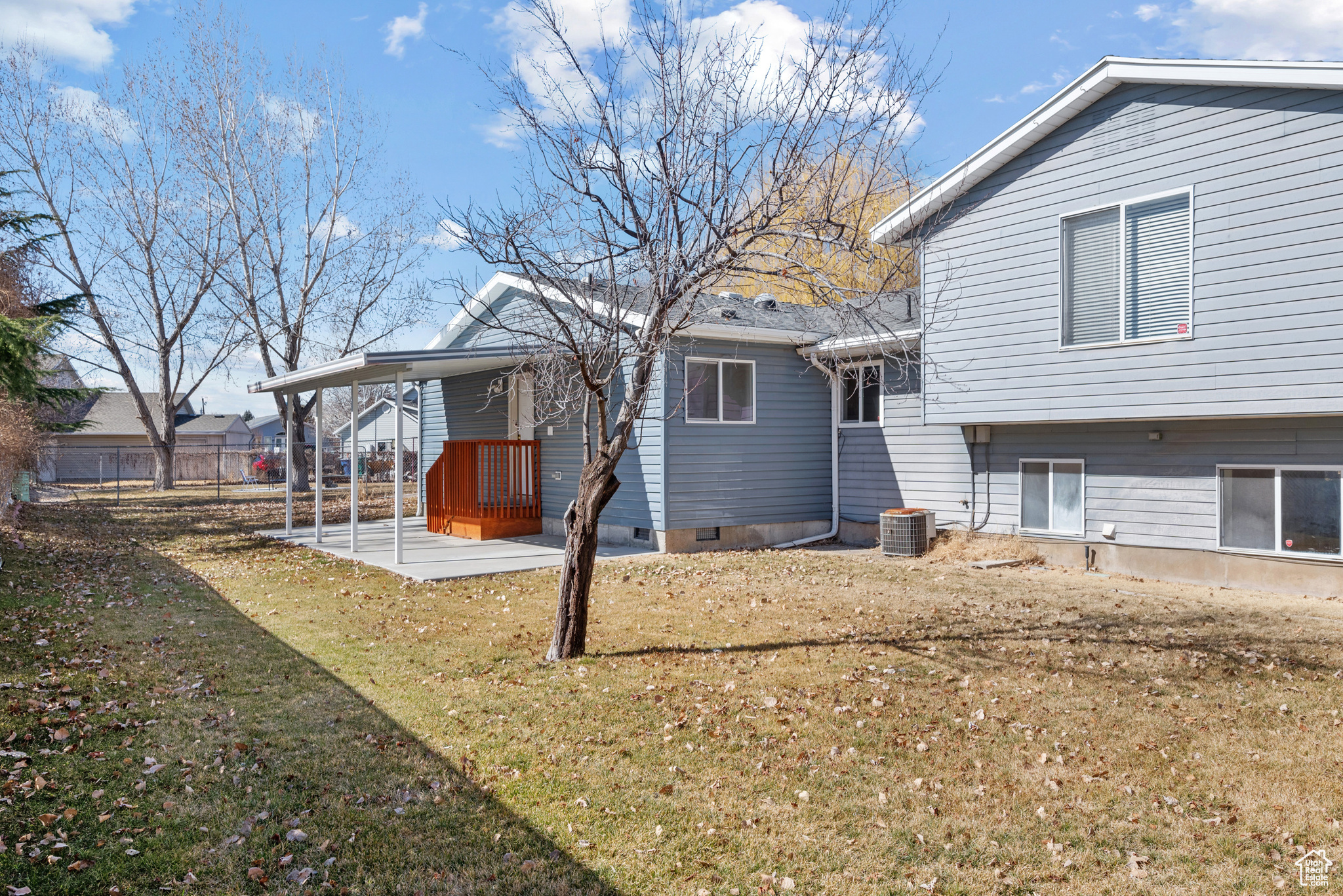 Rear view of property with central AC unit and a lawn