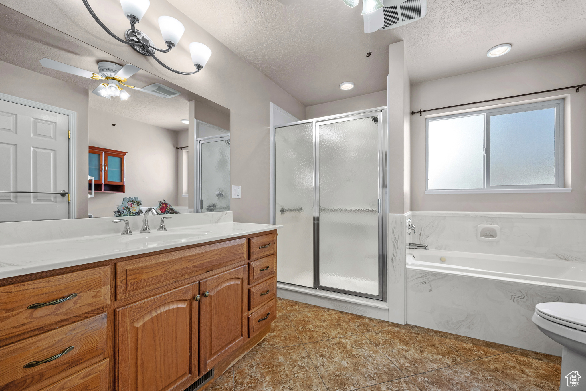 Bathroom featuring a garden tub, visible vents, a textured ceiling, and vanity
