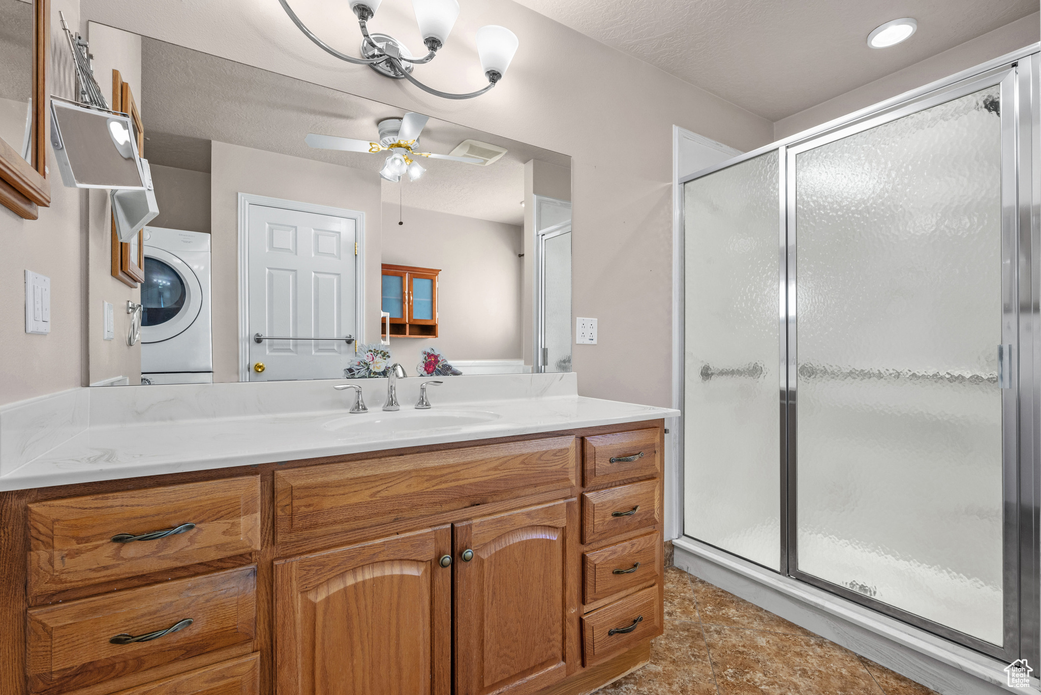 Bathroom with ceiling fan, washer / clothes dryer, a stall shower, and vanity