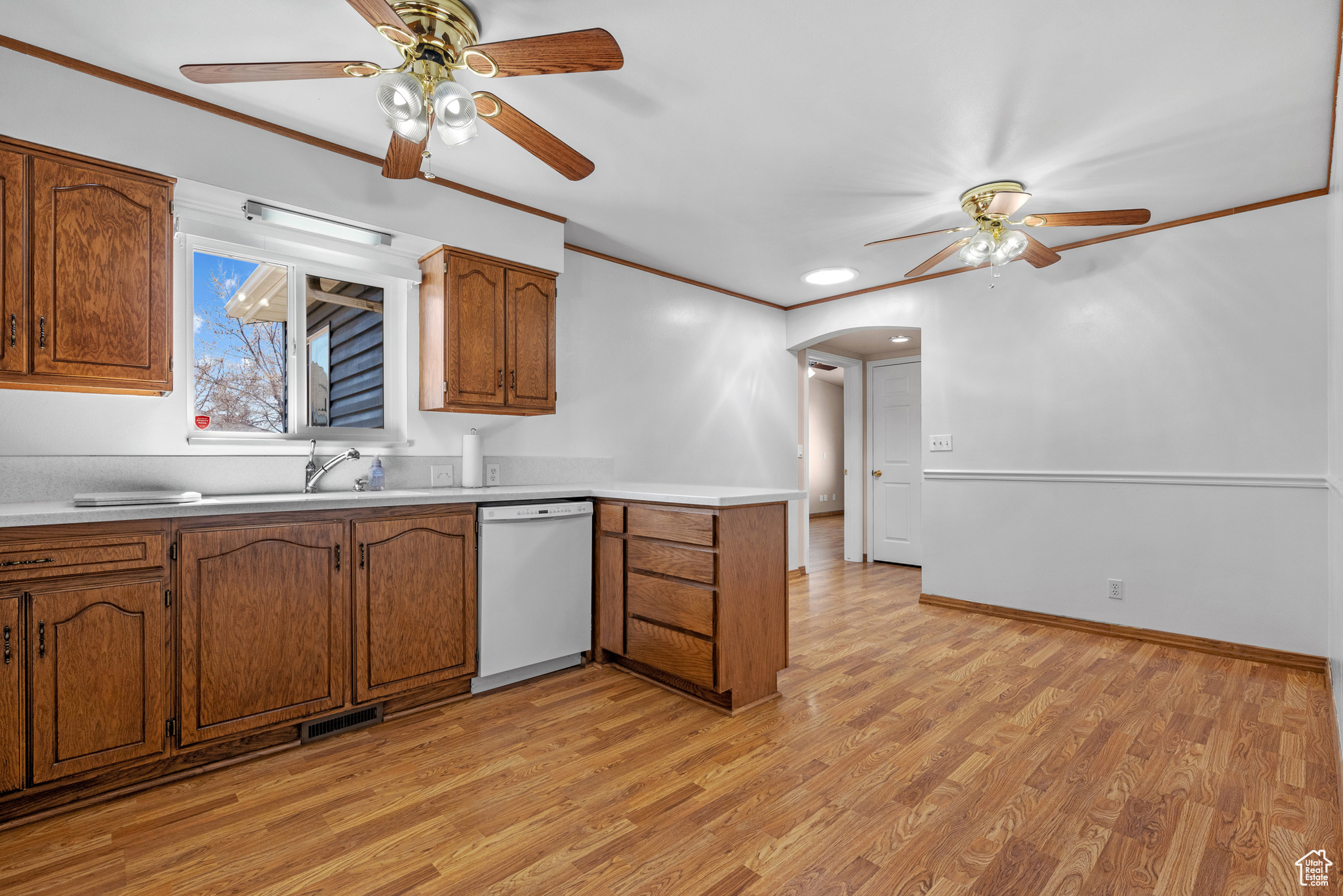 Kitchen featuring visible vents, dishwasher, ornamental molding, brown cabinets, and light countertops