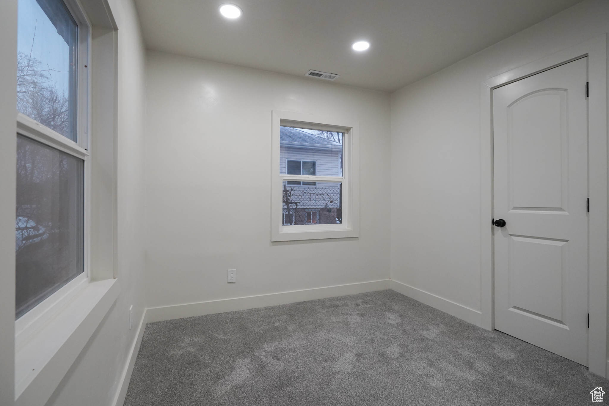 Carpeted spare room with baseboards, visible vents, and recessed lighting