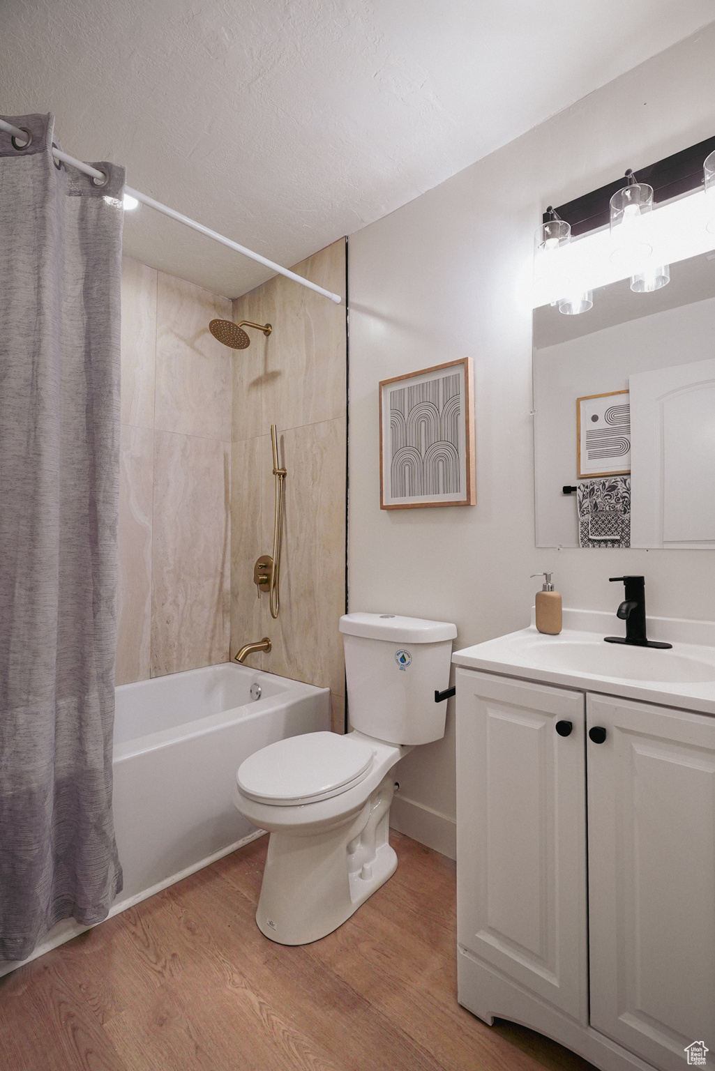 Full bathroom with a textured ceiling, toilet, shower / tub combo, wood finished floors, and vanity