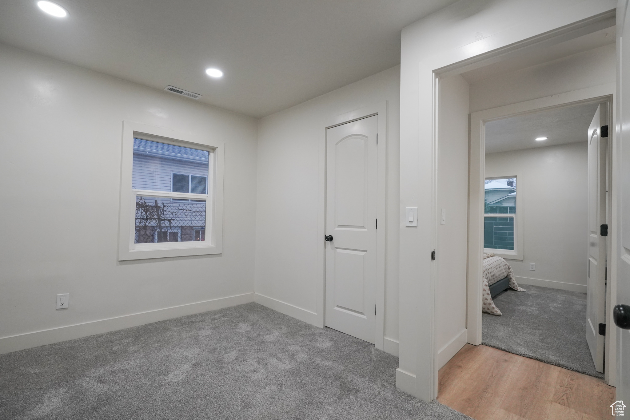 Interior space with baseboards, light carpet, visible vents, and recessed lighting