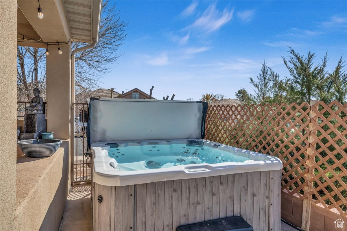 View of patio featuring fence and a hot tub