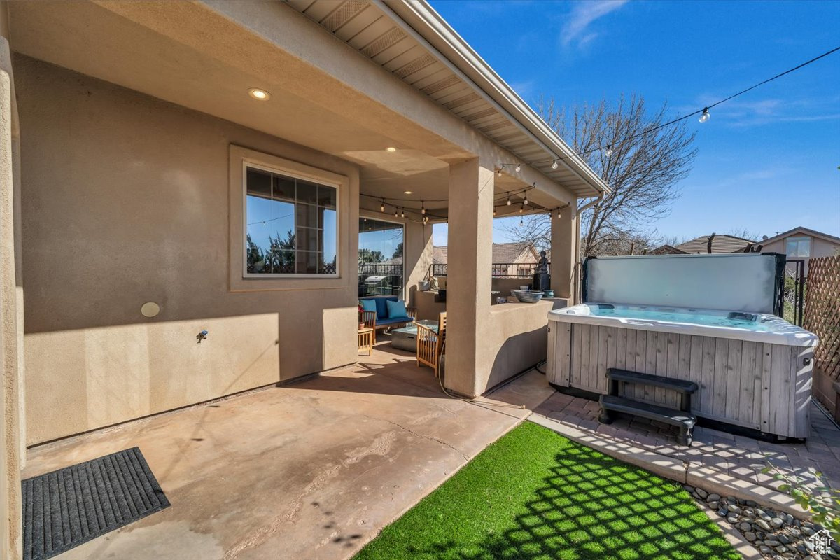 View of patio / terrace with a hot tub and fence