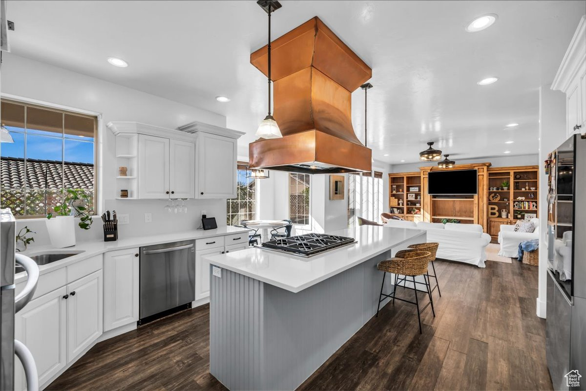 Kitchen featuring appliances with stainless steel finishes, pendant lighting, light countertops, and open floor plan