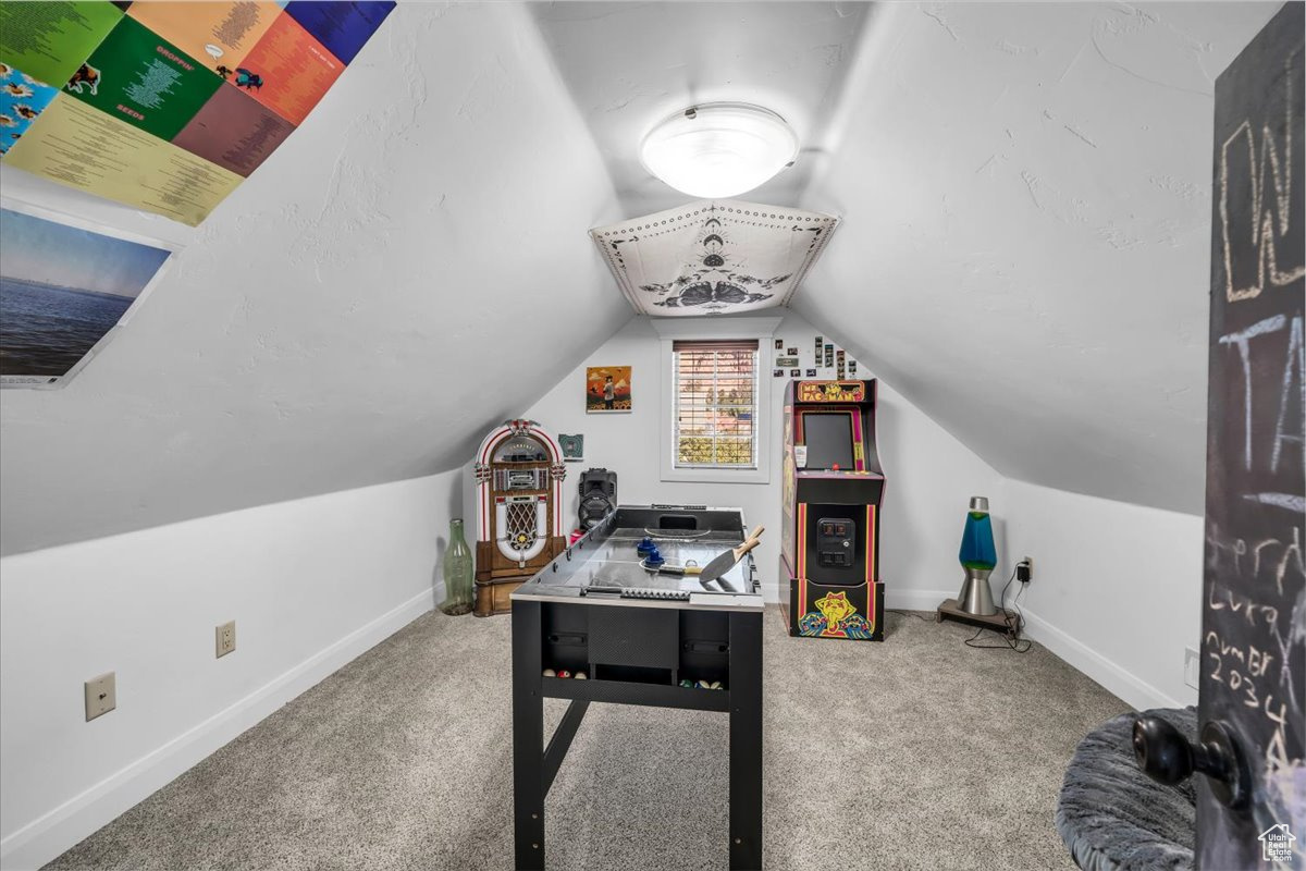 Recreation room with lofted ceiling, carpet floors, and baseboards