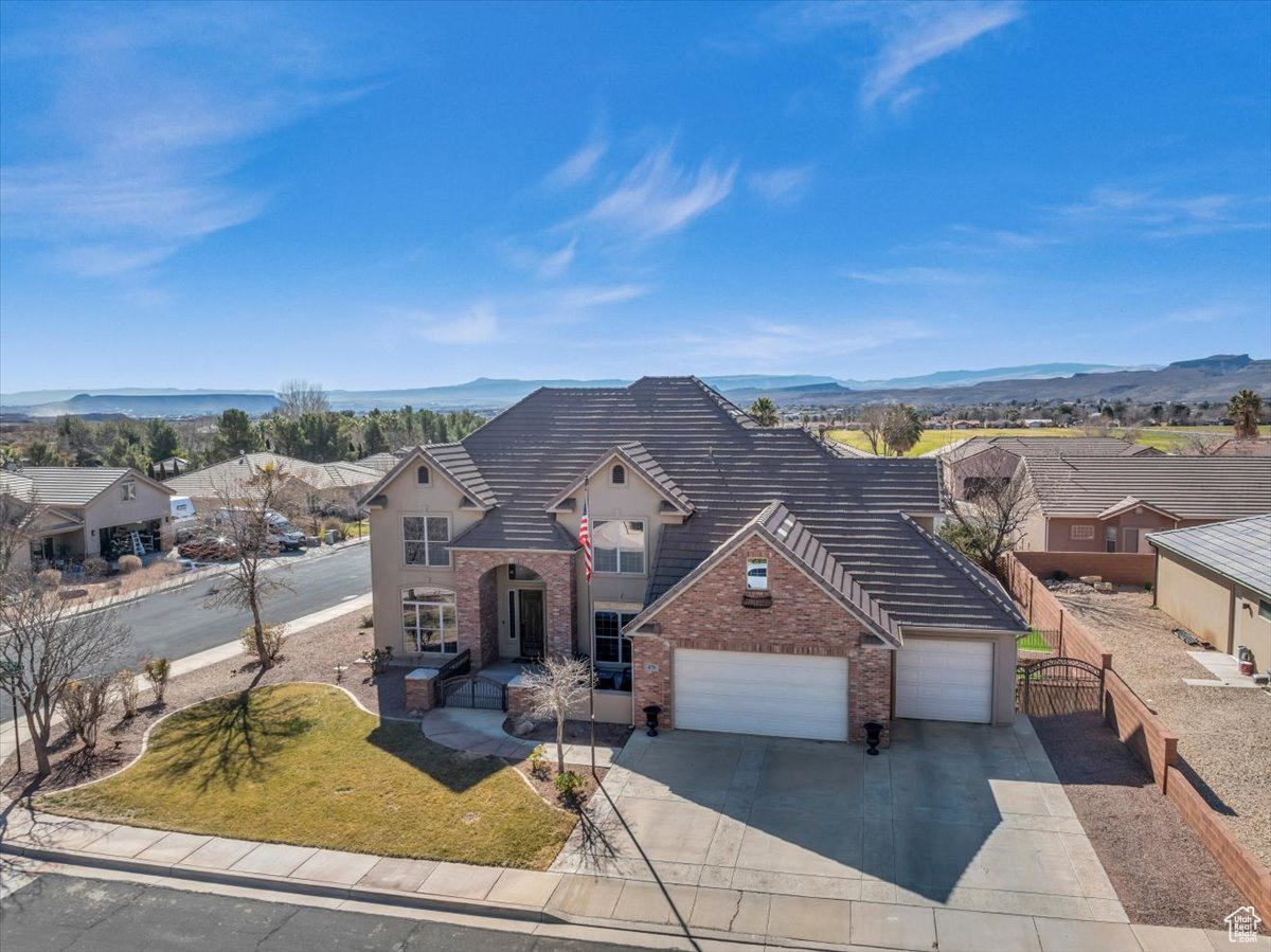 View of front of house featuring a garage, a mountain view, concrete driveway, and brick siding